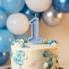 Dabīgā vaska ciparu svece "1" uz dzimšanas dienas tortes ar zilu balonu dekoru.